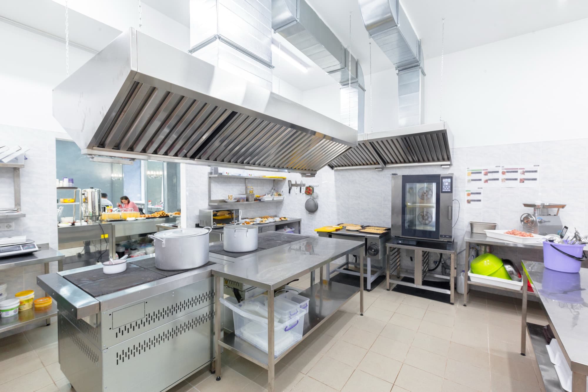 Bright stainless steel hotel kitchen with long work tables