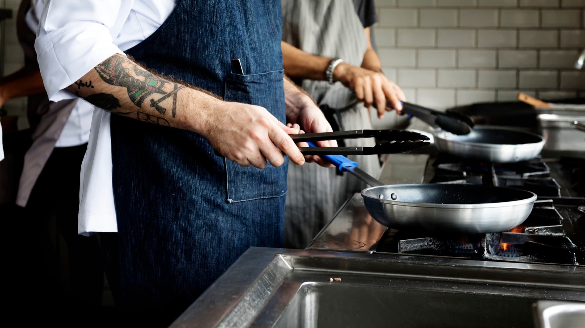 Chef cooking over a high flame in a restaurant kitchen
